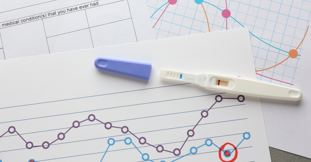 Photo of a pregnancy test sitting on top of medical provider forms and cycle tracking graphs